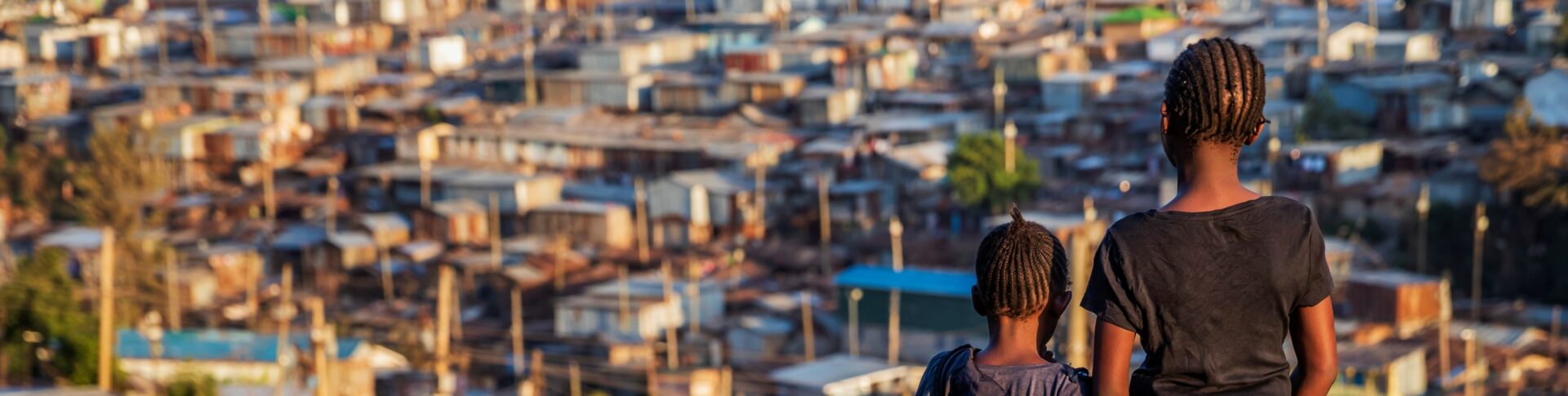 African little girls standing in trash and looking at Kibera slum, Kenya, East Africa